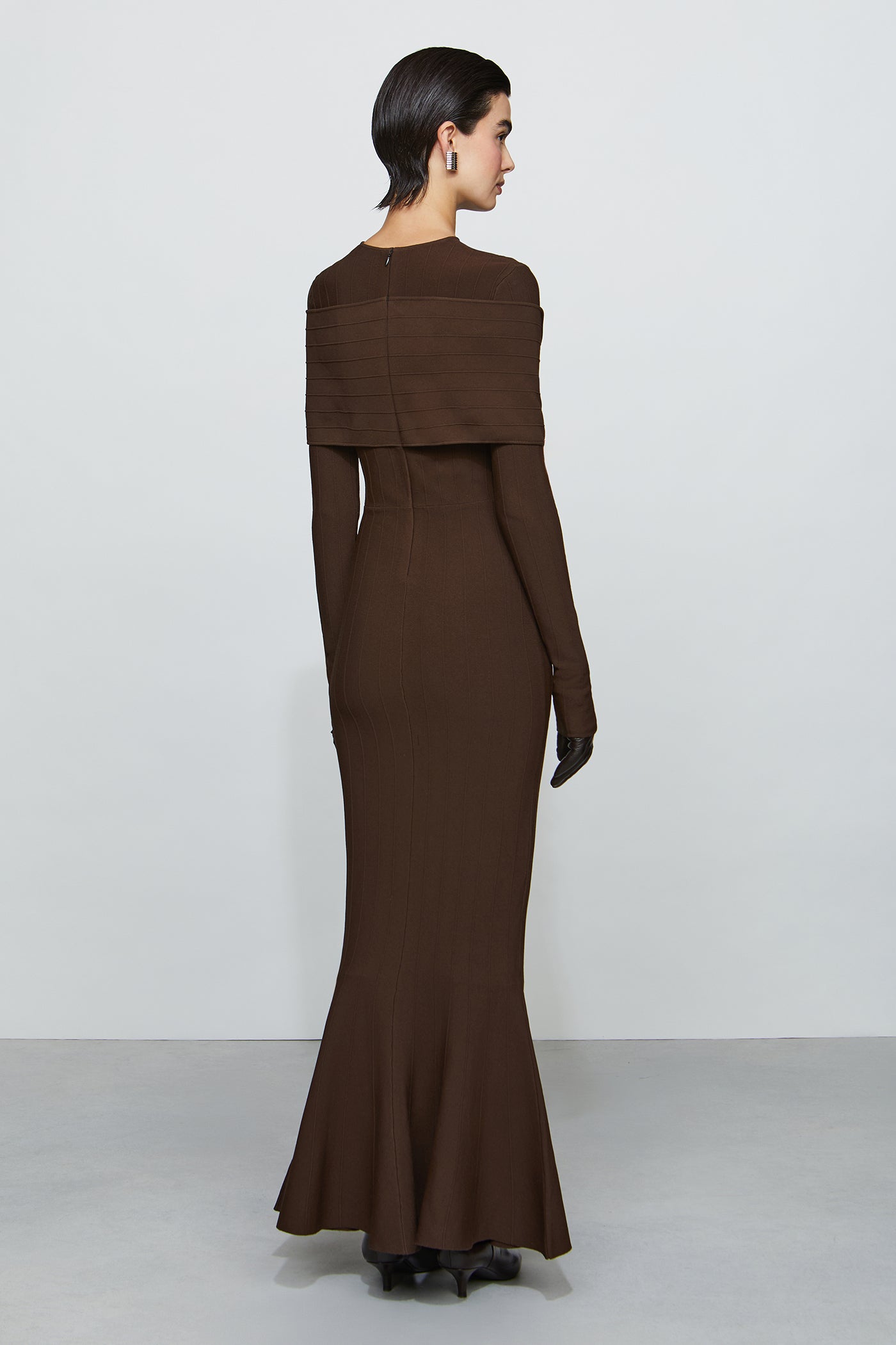 Woman wearing a brown long dress with a fitted silhouette on a white background