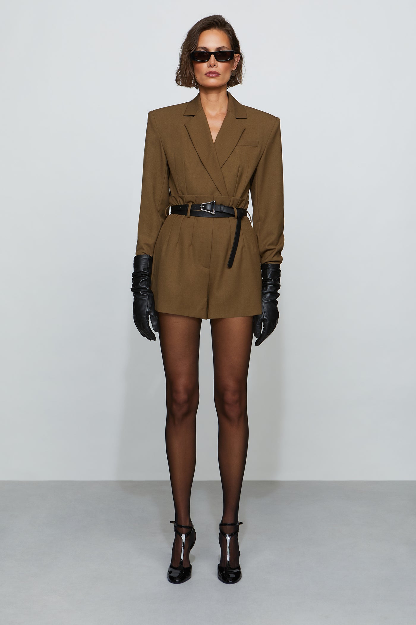 Woman wearing a brown suit with black gloves and shoes on a white background