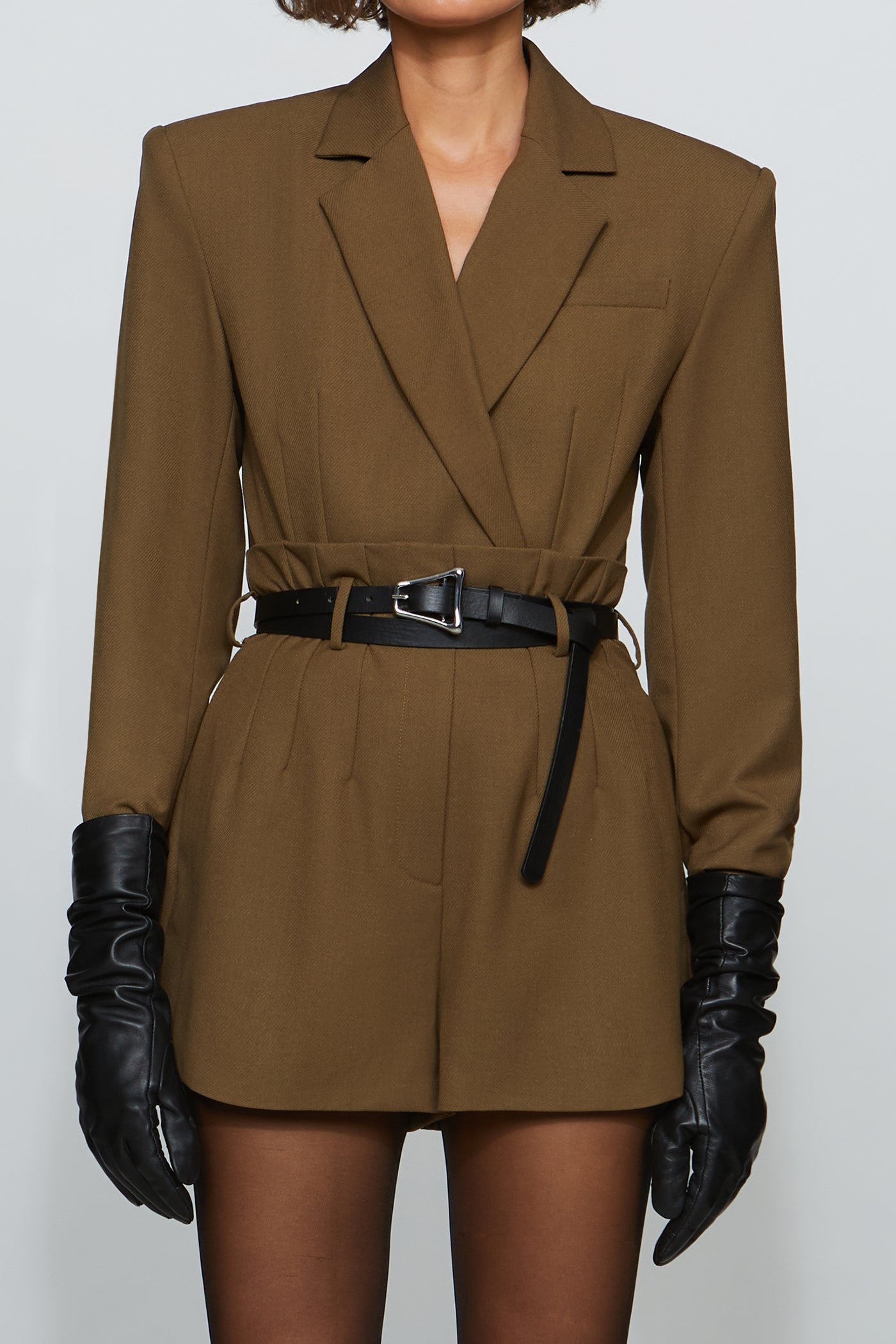 Woman wearing a brown suit with black gloves on a white background