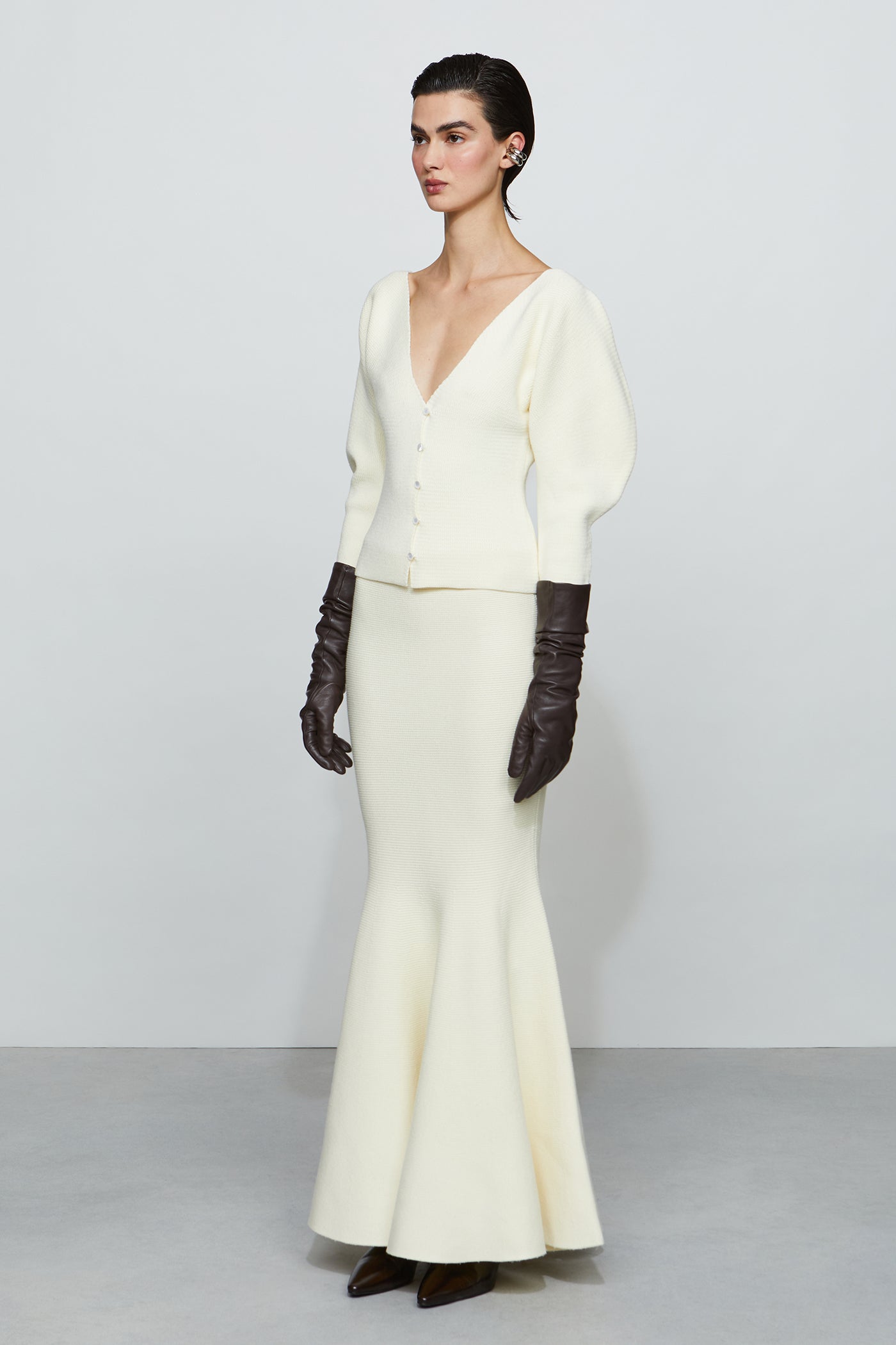 Woman wearing a white outfit with long gloves against a plain background