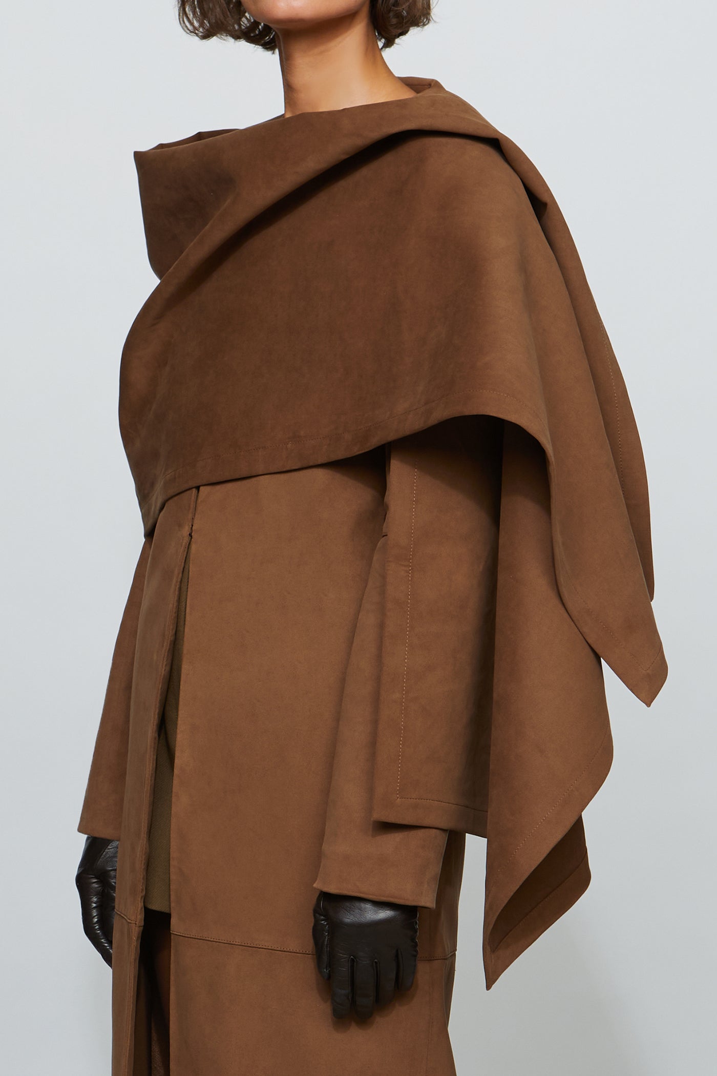 Brown draped garment worn by a person on a plain background