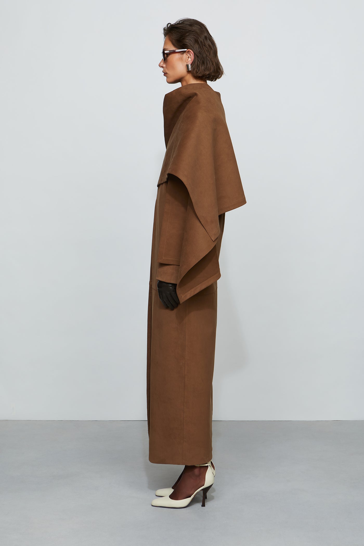 Woman wearing a long brown coat against a white background