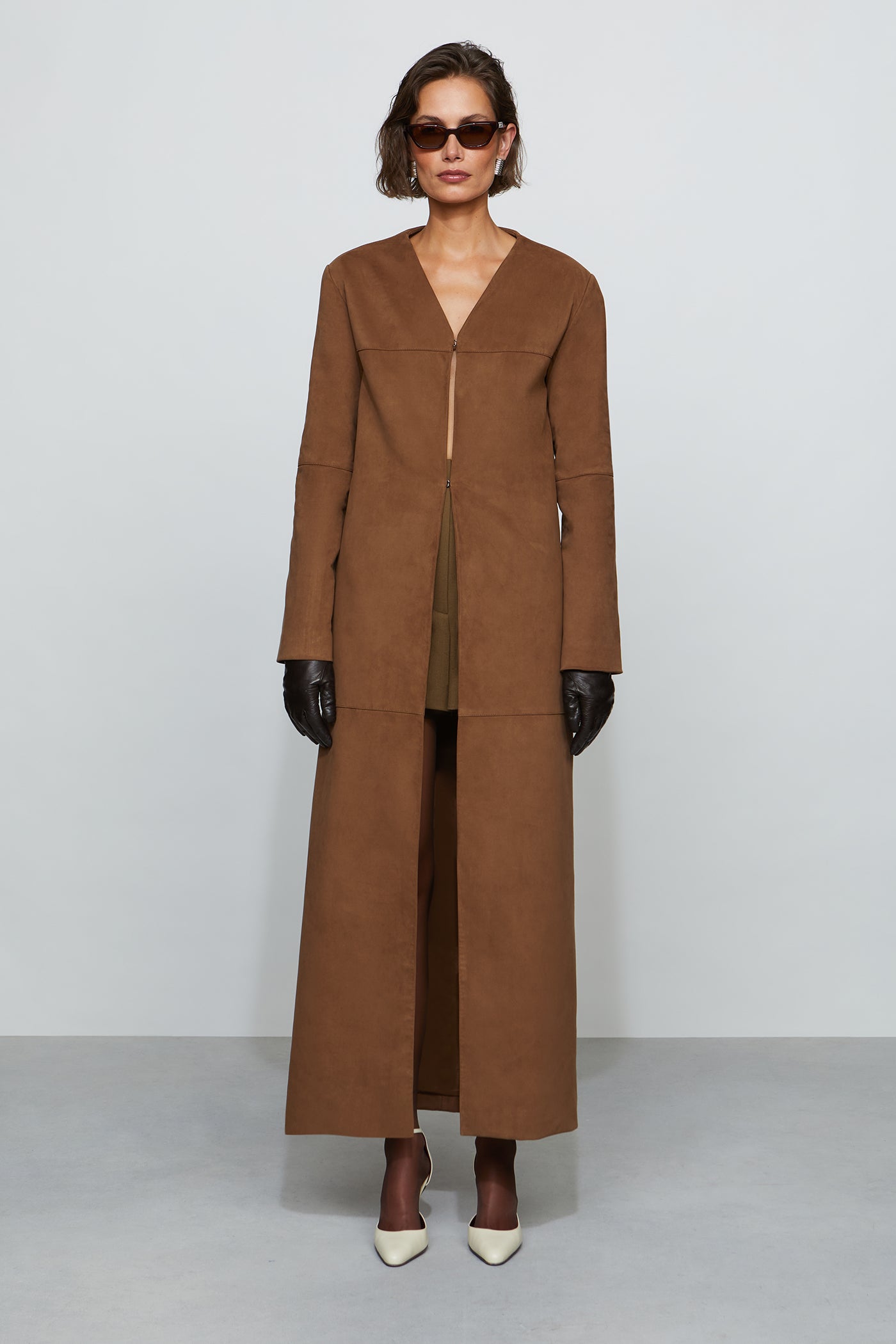 Woman wearing a long brown coat against a white background