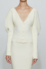 Cream-colored outfit with a cardigan and skirt on a plain background